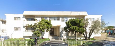 A white building with a black car parked in front.