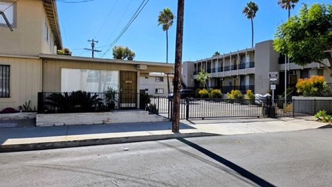 A street view of a residential area with a house and apartment buildings.