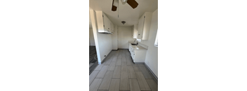 A kitchen with white cabinets and a fan.