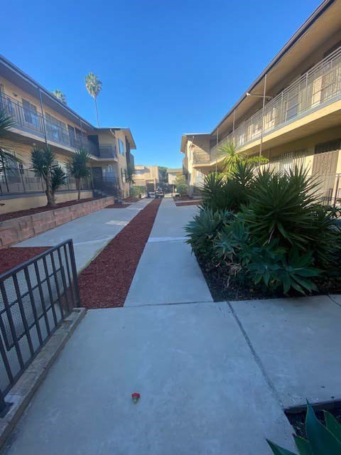 A red brick pathway leads to a building with a black gate on the left.