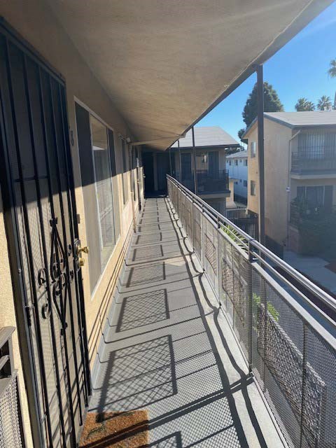 A long balcony with a metal railing and a brown rug on the floor.