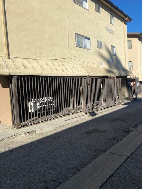 A car is parked behind a metal gate on a street.