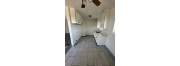 A kitchen with white cabinets and a fan.