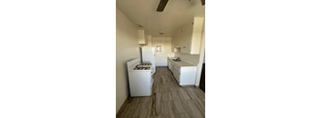 A white kitchen with a wood floor and white appliances.