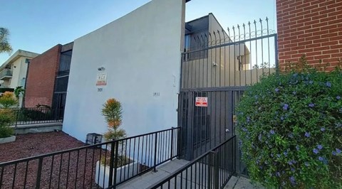 A white building with a black gate and a sign that says "307".
