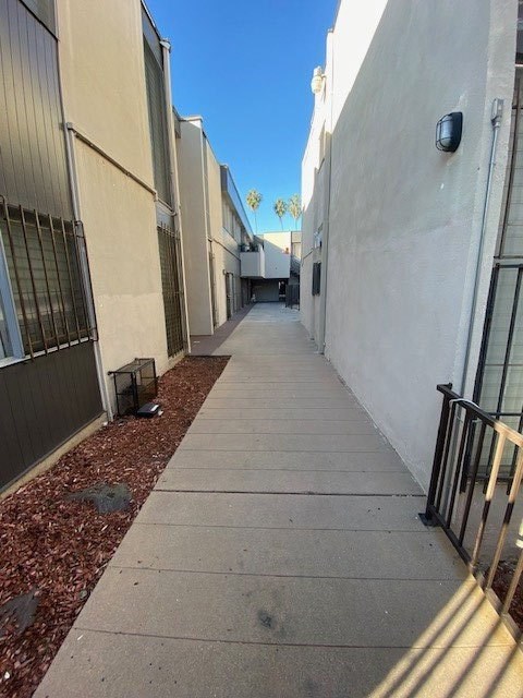 A narrow alley with a sidewalk and a metal railing.