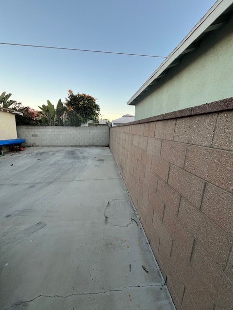 A backyard with a concrete floor and a brick wall.