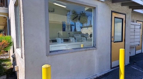 A yellow pole stands in front of a building with a window.