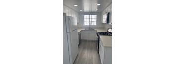 A kitchen with white cabinets and a refrigerator.
