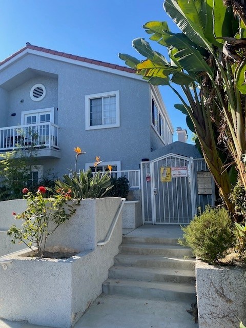A grey house with a red roof and a white fence.