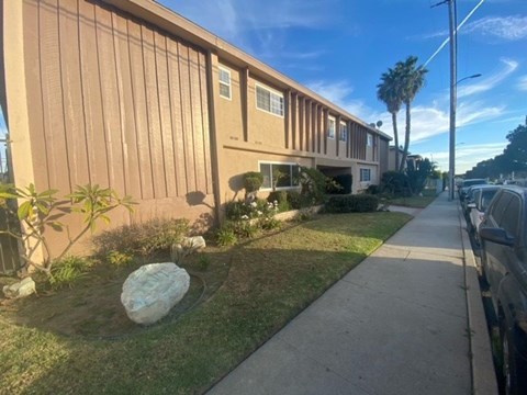 A building with a brown facade and a large rock in the front yard.