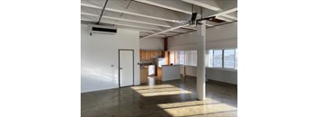 A large, empty room with a kitchen area in the background.