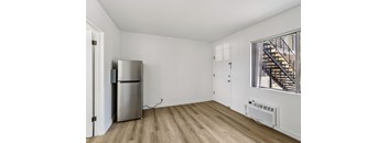 A room with a stainless steel refrigerator and a wooden floor.