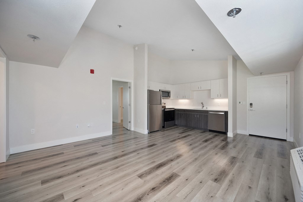 the living room and kitchen of an apartment with wood floors and white walls  at Track 281 Apartments, Sacramento, CA