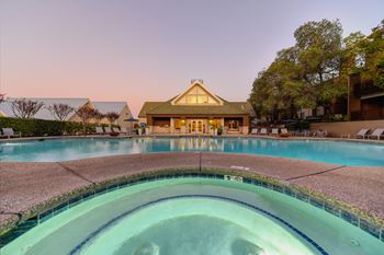 Spa at dusk.  Lights inside the pools and spa are illuminating the water.  View of the leasing office is in the distance.at Folsom Ranch, Folsom, CA, 95630