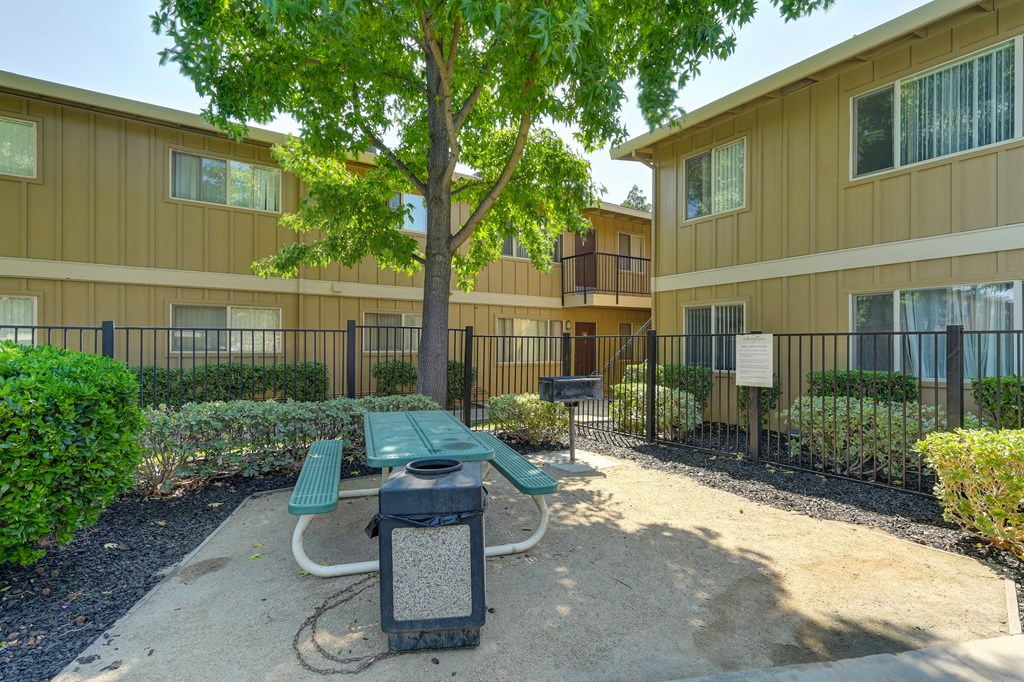 Asbury Place community picnic table and trash can outside  in a courtyard area