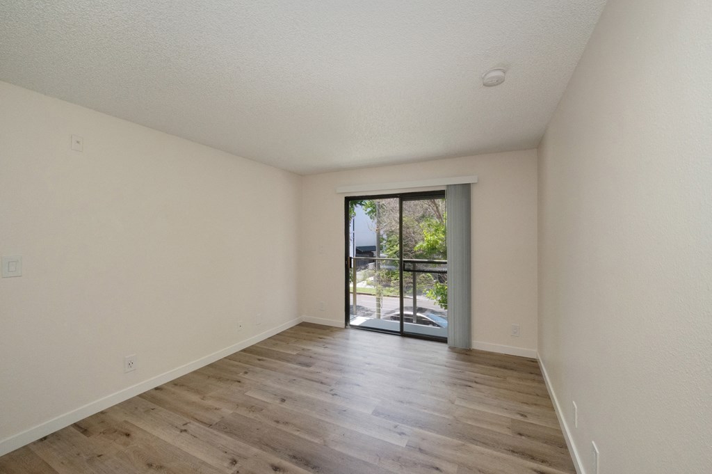 a bedroom with hardwood floors and white walls at Croft Plaza Apartments, West Hollywood California