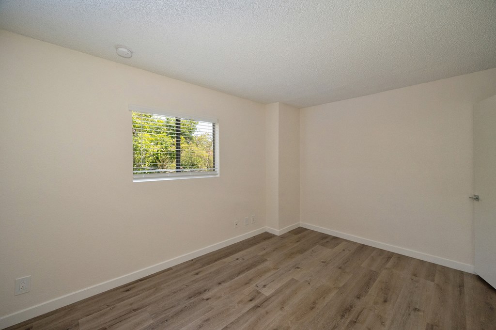 a bedroom with a large window and hardwood floors at Croft Plaza Apartments, West Hollywood, 90069