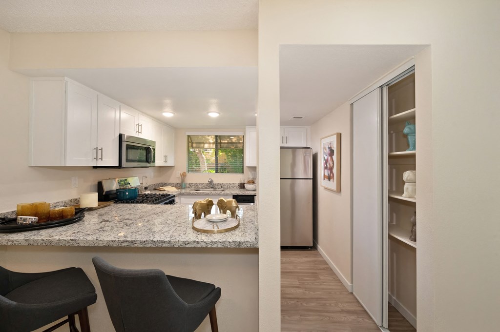 a view of a kitchen and a living room with a stainless steel refrigerator and microwave