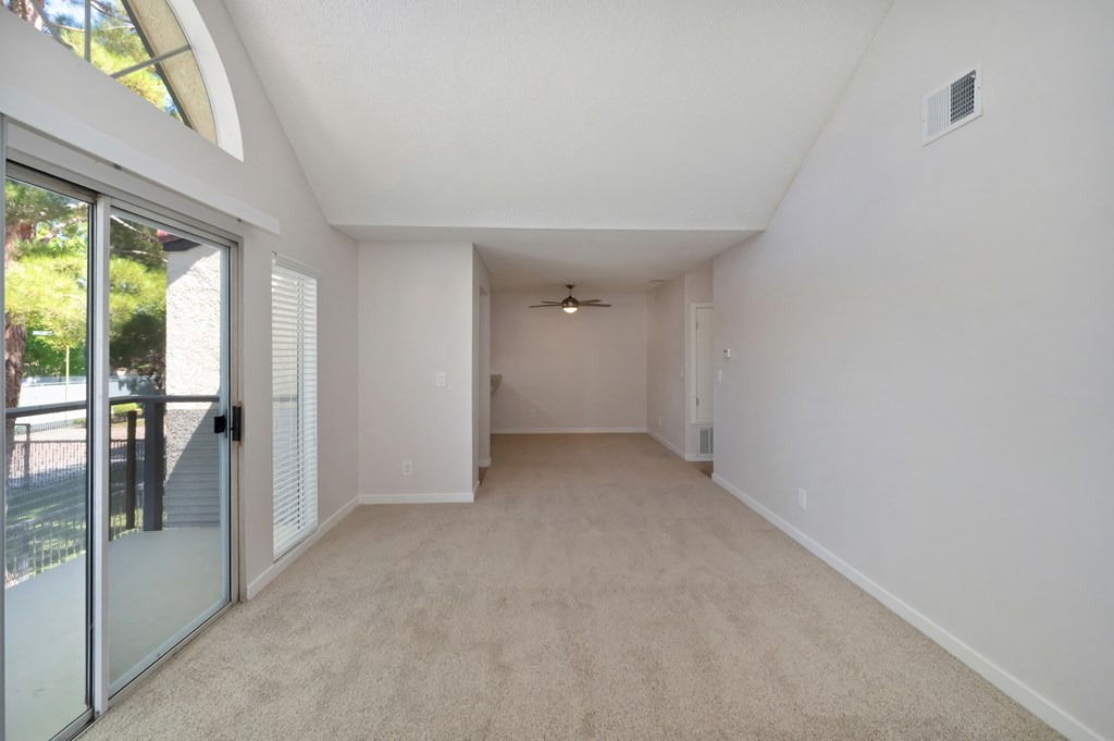 an empty room with a sliding glass door and a ceiling fan