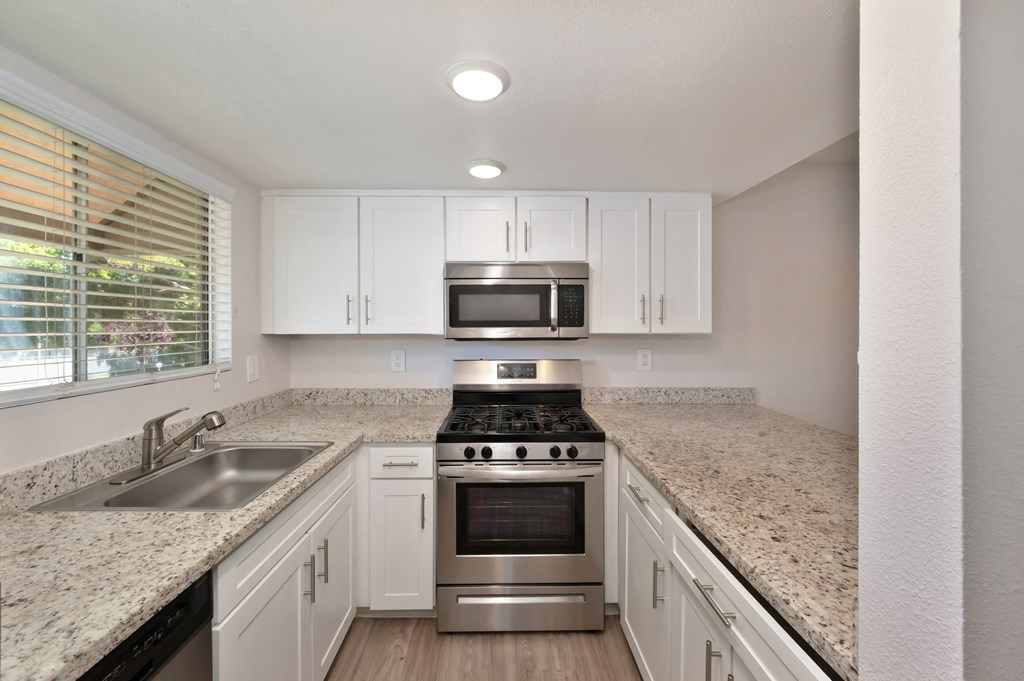 a kitchen with white cabinets and granite countertops