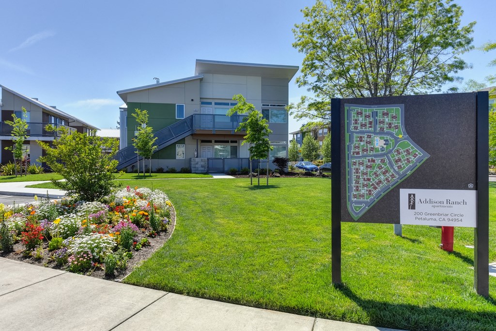 Addison Ranch Apartments Company Sign with  Wood Chip Floor, Flower Beds, Fire Hydrant, and Road at Addison Ranch Apartments, California, 94954