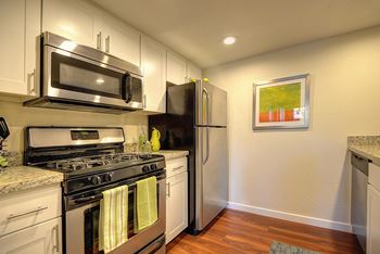 Model Home Kitchen with Gas range with microwave above it and stainless refrigerator.