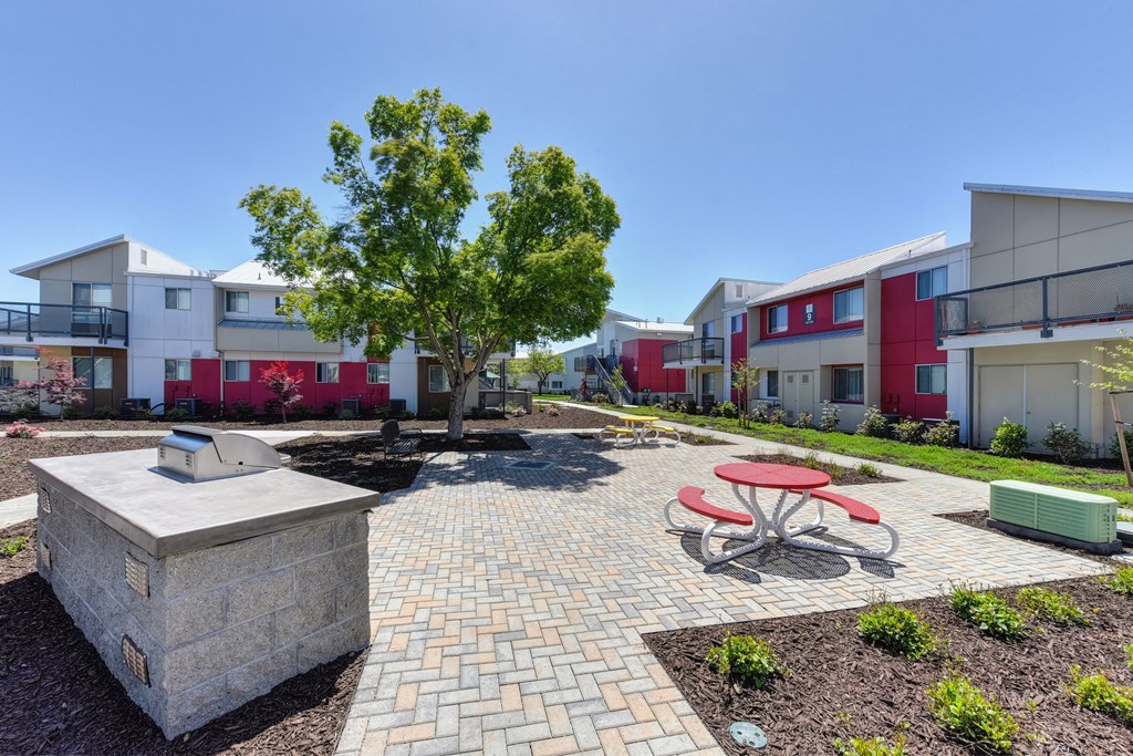 Outdoor Lounge Space with Red Picnic Table, Trees, Wood Chip Floor, Apartment Exterior at Addison Ranch Apartments, California, 94954