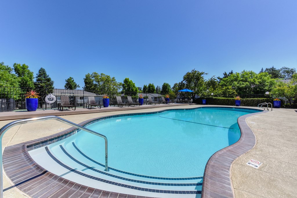 Swimming Pool entrance with bright blue gardening pots along the fence-line with plants in the distance.at The Renaissance Apartments, California