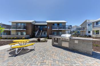 Outdoor Lounge Space with Red Picnic Table, Trees, Wood Chip Floor, Apartment Exterior at Addison Ranch Apartments, Petaluma, CA