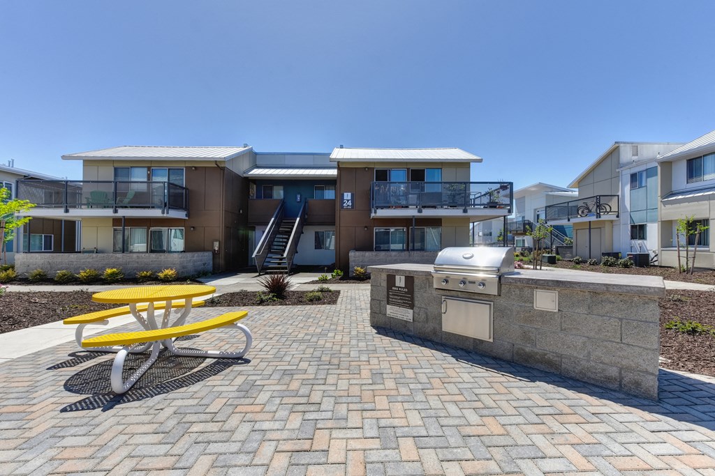 Outdoor Lounge Space with Red Picnic Table, Trees, Wood Chip Floor, Apartment Exterior at Addison Ranch Apartments, Petaluma, CA, 94954