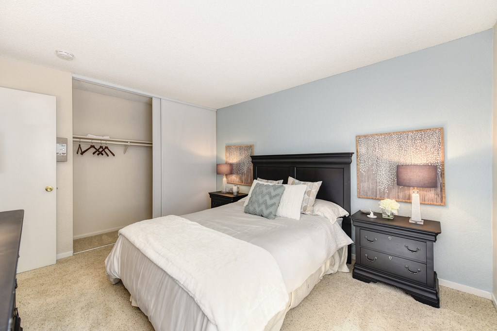 Master bedroom in the model home. Queen size bed with two nightstands. Large closet and carpeting on the floors.at The Renaissance Apartments, Citrus Heights, CA