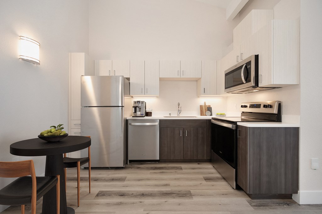 a kitchen with stainless steel appliances and a small table with chairs  at Track 281 Apartments, California, 95811