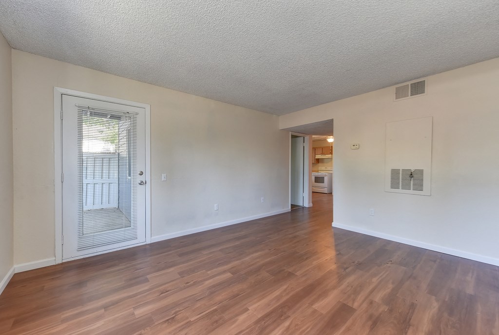 Ground floor apartment home with access to the patio.  Hardwood inspired flooring through out and views of the kitchen in the distance.