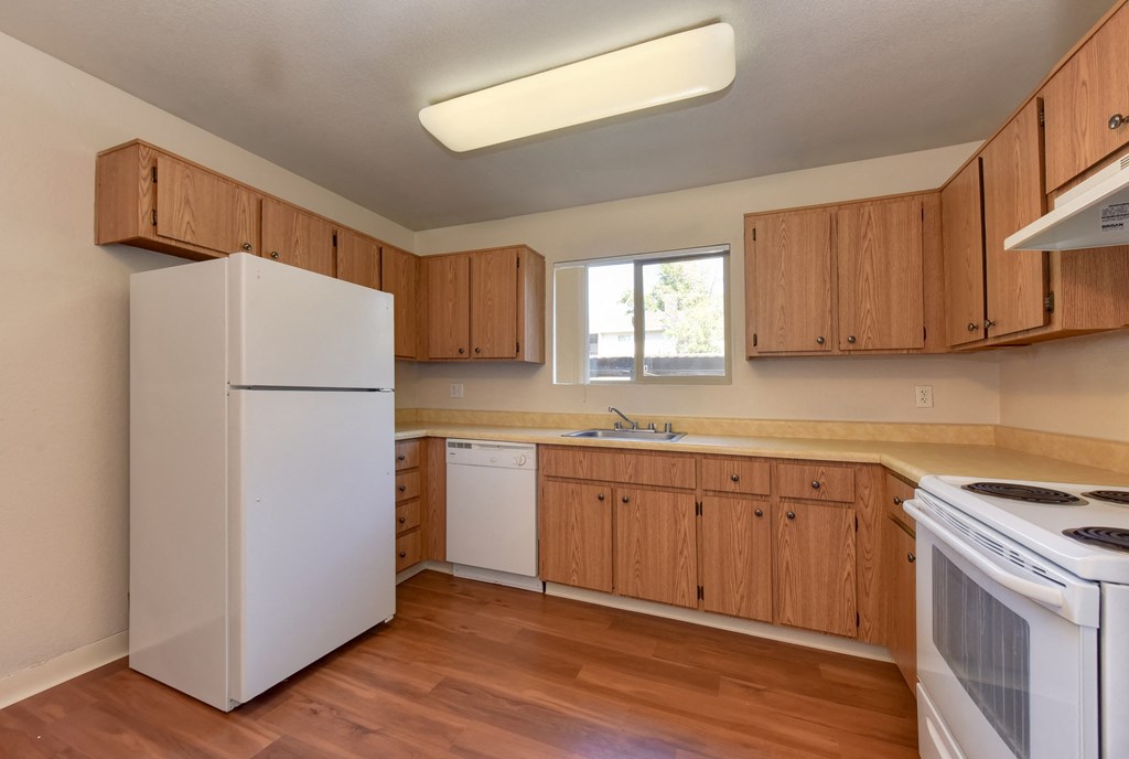 Kitchen with light brown cabinetry and all major kitchen appliances in white.