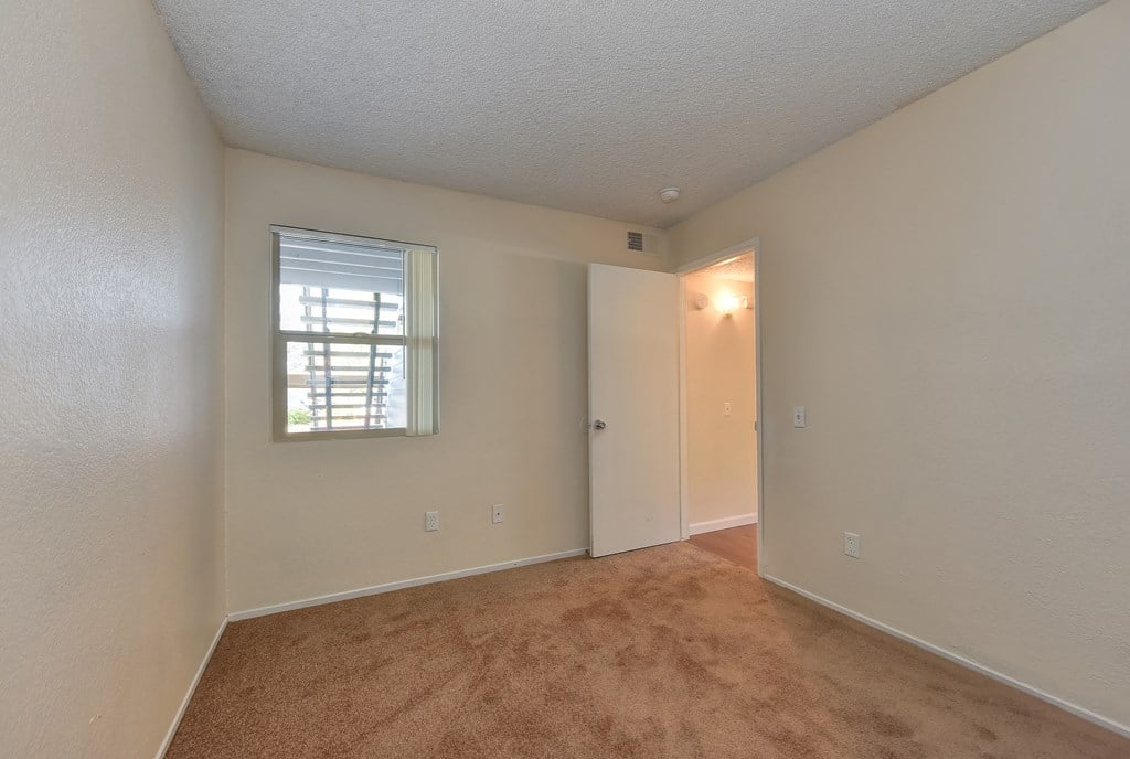 Bedroom with smaller window that looks out towards the entryway of the apartment.
