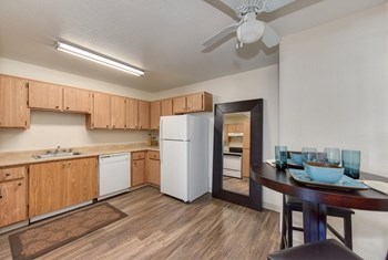 Kitchen and dining area with hardwood inspires flooring, tall table off to the side with two chairs. - Photo Gallery 3