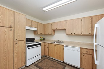 Kitchen area with multiple cabinets for storage, oven, stove, refrigerator, and dishwasher in white. - Photo Gallery 4