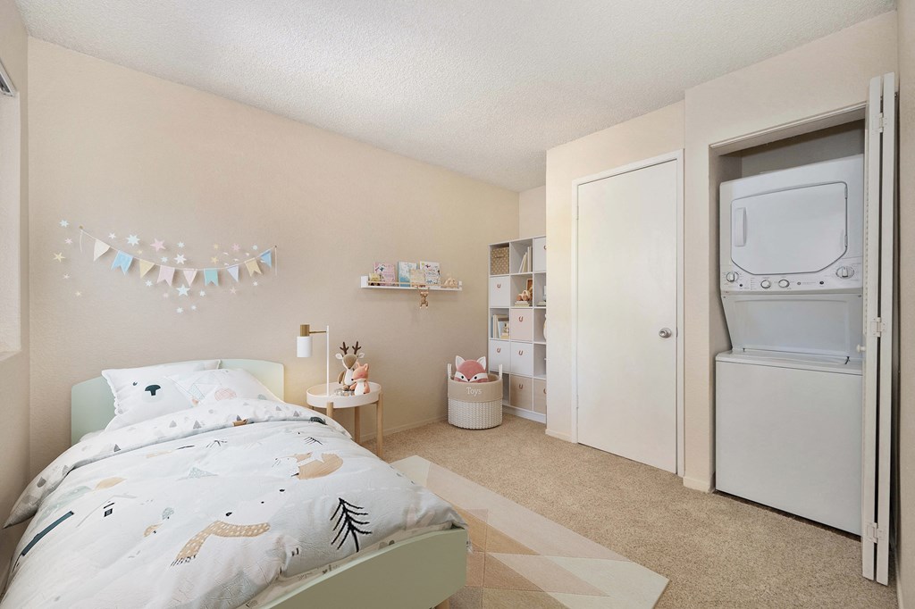 a bedroom with a bed, closet, and a washer and dryer