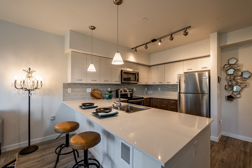 Model Home kitchen area with open island quartz countertop with 2 brown bar stools. 