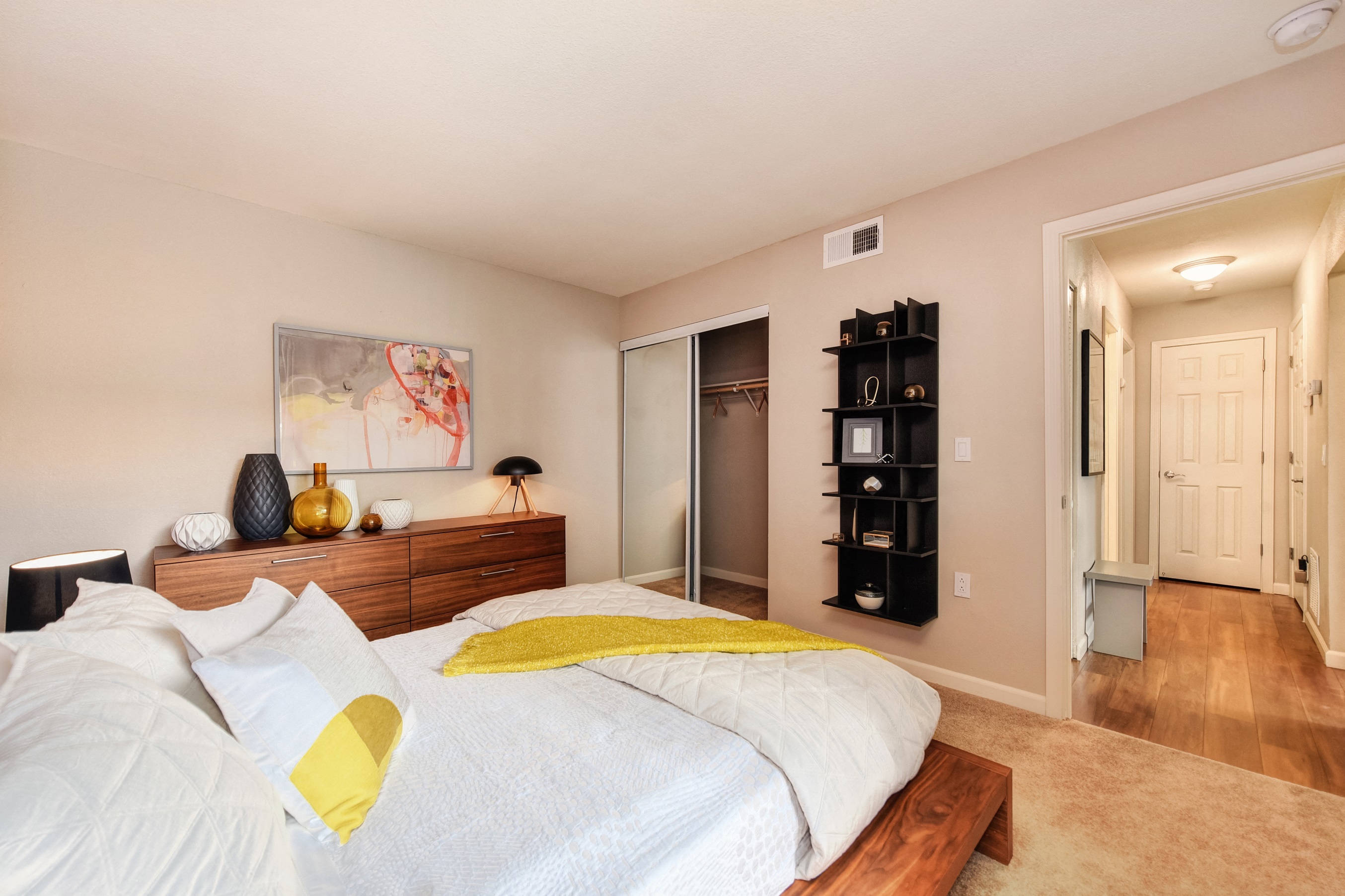Red Wall Bedroom with Full Sized Mattress and Wooden Frame, White Comforter and Yellow Blanket, Wood Dresser at Addison Ranch Apartments, California