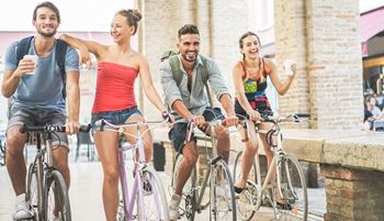 Four young adults riding bikes together.  Two people are enjoying coffee while biking at Addison Ranch Apartments, Petaluma, CA