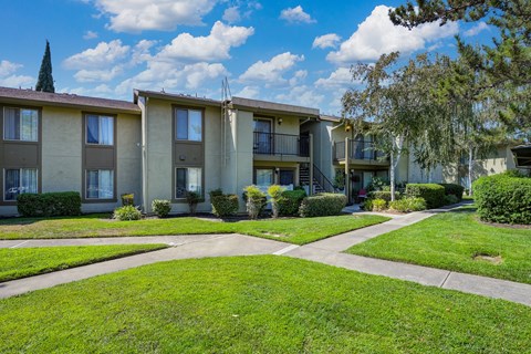 Breckenridge Village Community walk path with grass and mature landscaping and apartments in the distance.
