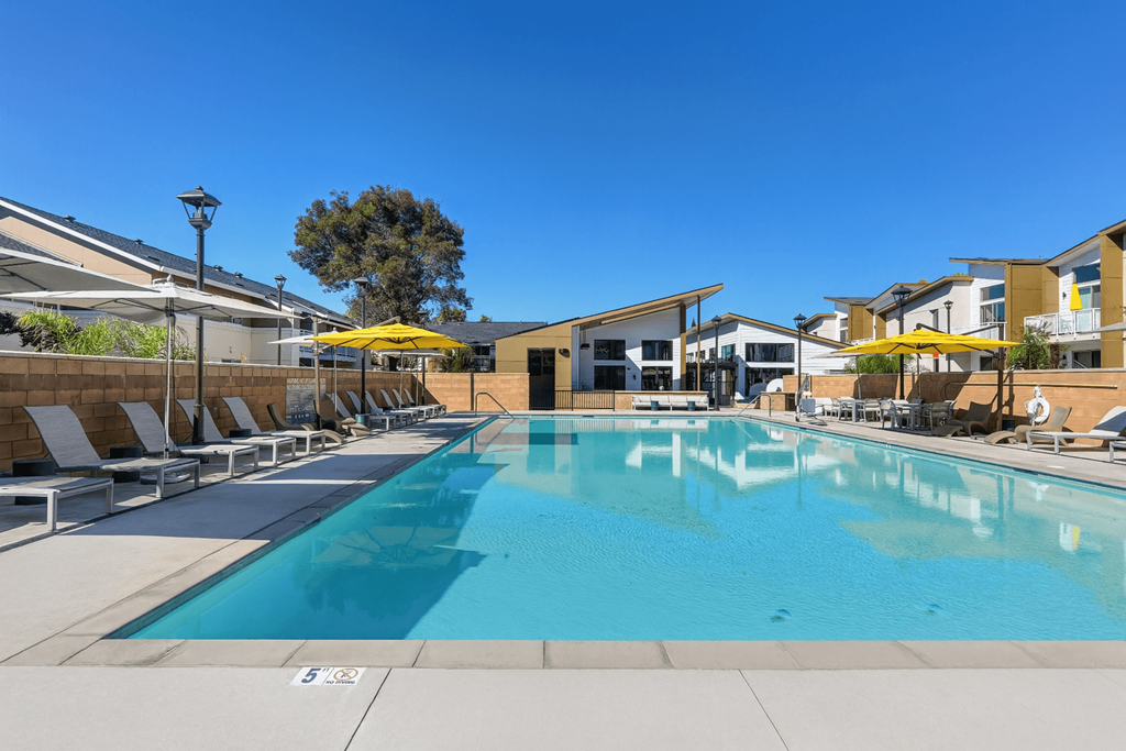 A large outdoor swimming pool with sun loungers and umbrellas.