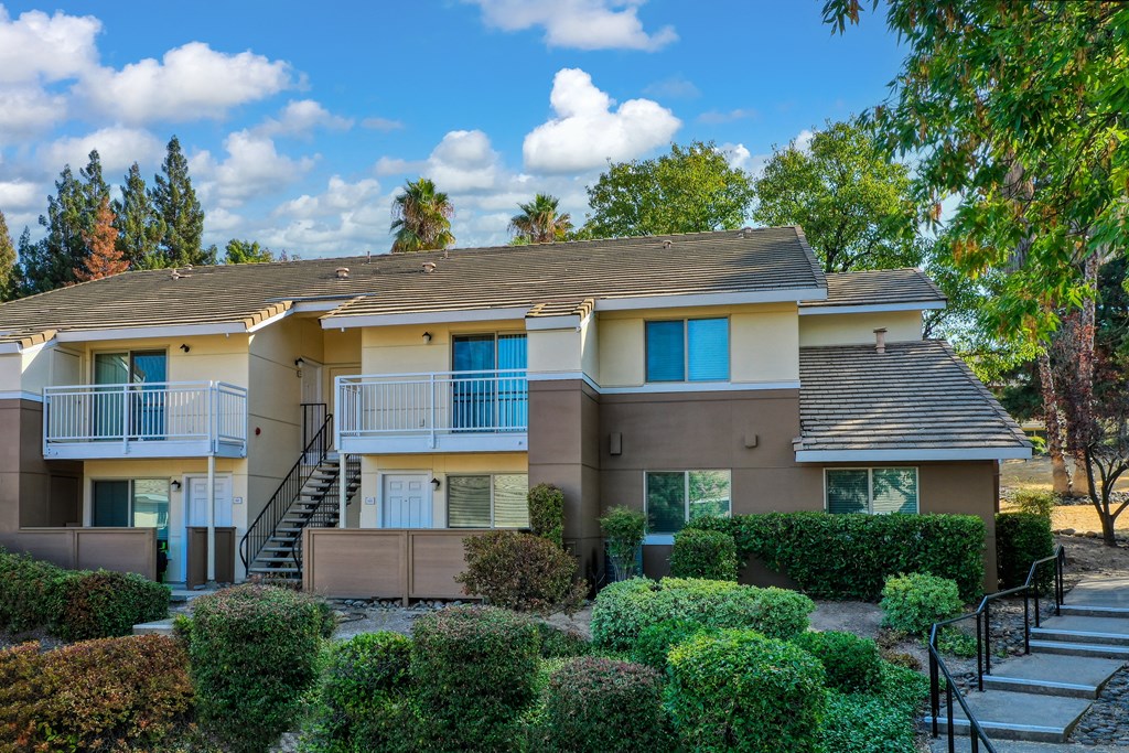 Exterior of Canyon Terrace Apartments with mature landscaping and walkway stairs on the right.