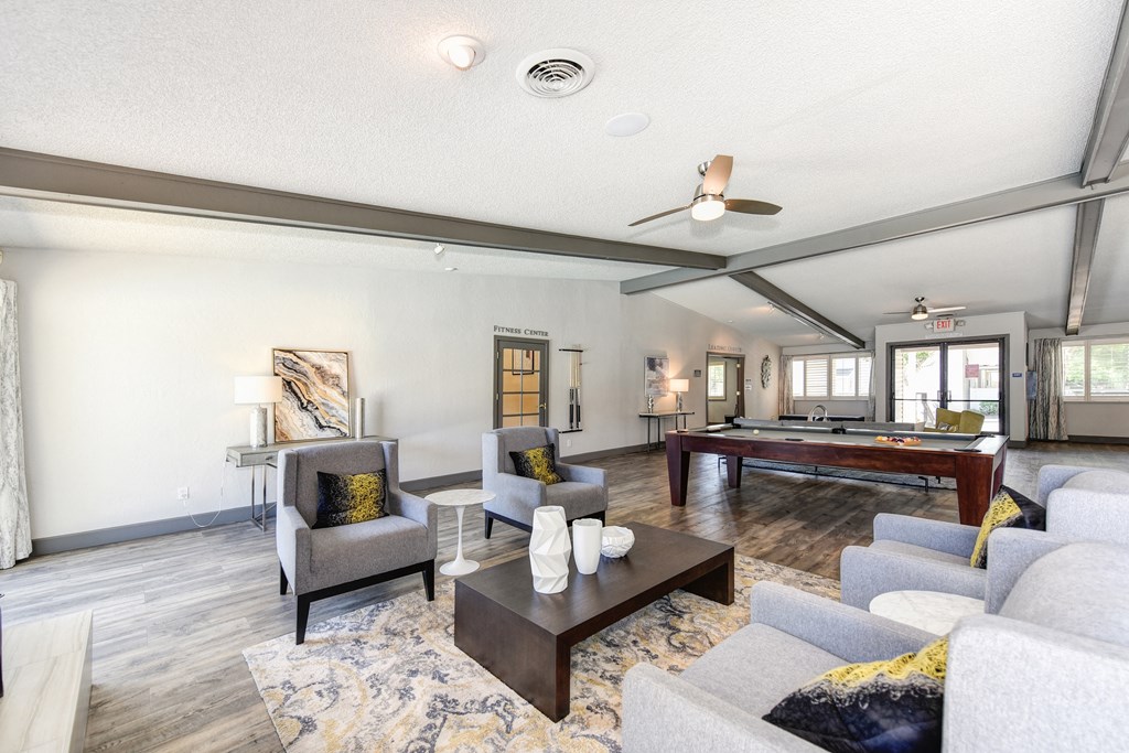 Clubhouse Sitting Area with Couches, White Tables and Pool Table in Distance at The Renaissance Apartments, California