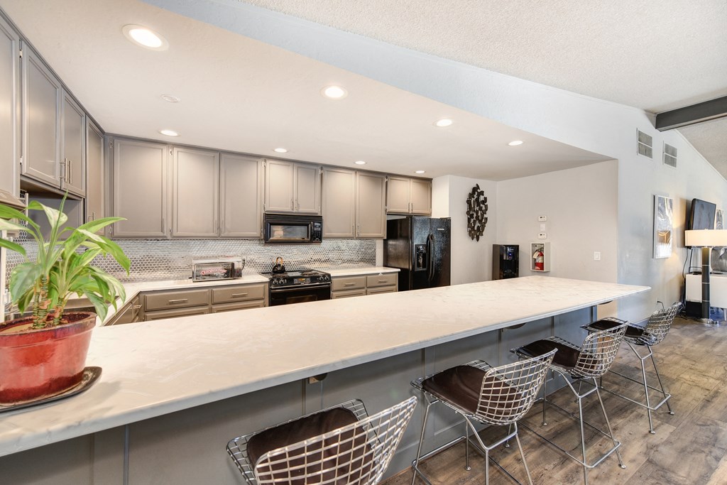 Clubhouse Kitchen with Bar Seating, White Counter, Cabinets and Refrigerator at The Renaissance Apartments, California, 95610