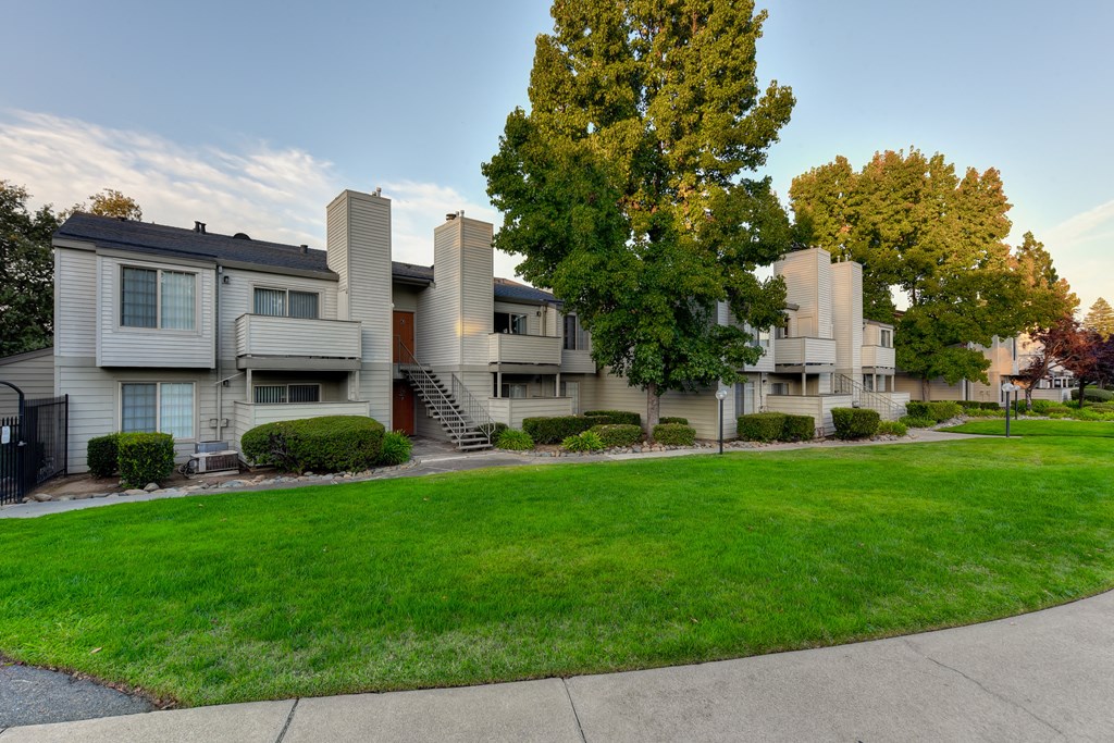 exterior view of apartments with lawns and trees at Cobblestone Creek Apartments