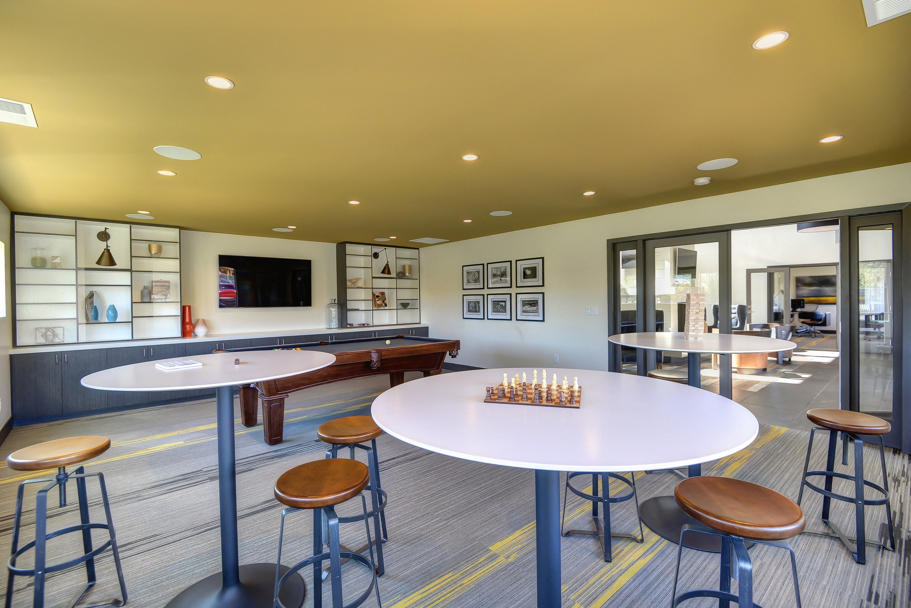 Community Clubhouse Game Room with Round Desk, Stools, Chess Set, Mounted Flatscreen Television at Addison Ranch Apartments, Petaluma, CA