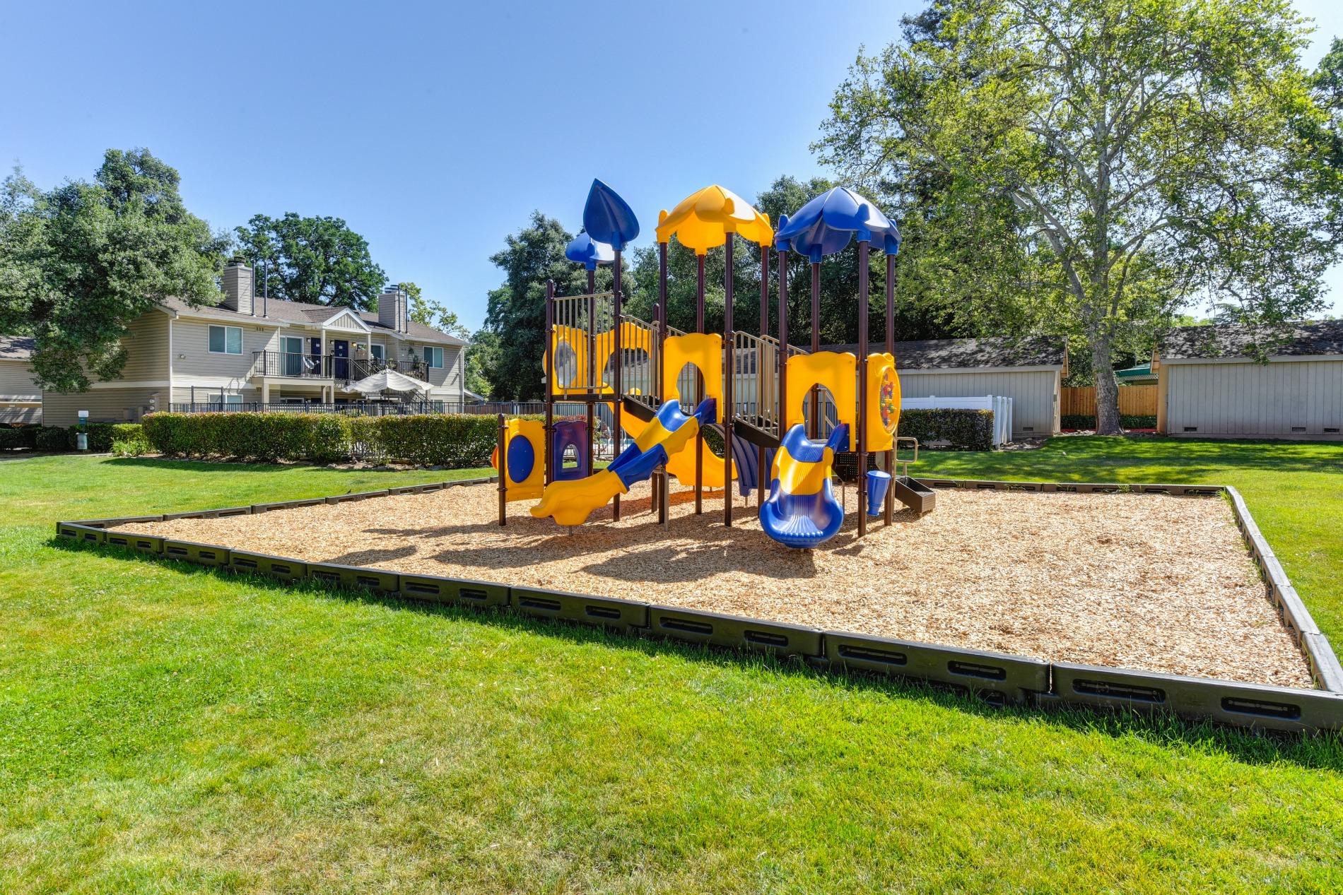 Playground with Sand, Grass and Apartment Exteriors at Hidden Oaks Apartments, Citrus Heights, CA, 95621